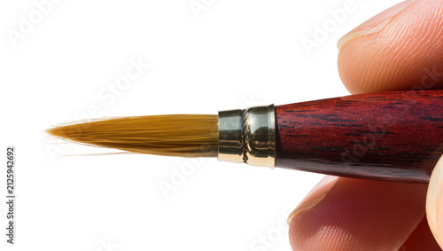 Bild auf Leinwand Human fingers holding a fine-tipped paintbrush with wooden handle, isolated on t