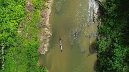 Top-down drone following longboat along Sungai Tembeling through primary tropical rainforest, Al-Sultan Abdullah Royal Tiger Reserve, Pahang, Malaysia