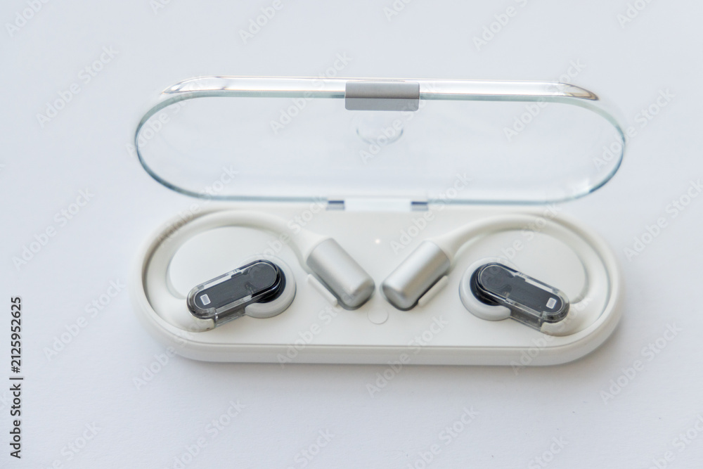 Fototapeta premium Wireless open ear headphones in charging case on white surface
