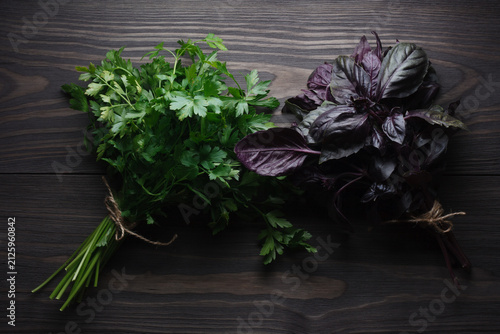 Fresh bunch parsley and purple basil on dark wooden table