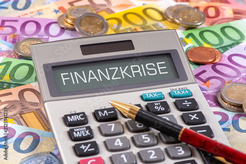 Auf vielen Euroscheinen liegt ein Taschenrechner mit dem Wort Finanzkrise im Display - FOTOMONTAGE