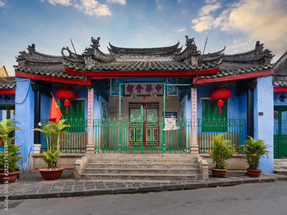 Obraz premium The historic Trung Hoa Assembly Hall in Hoi An, Vietnam, displaying vibrant Chinese architecture with red lanterns, green iron gates, and blue walls