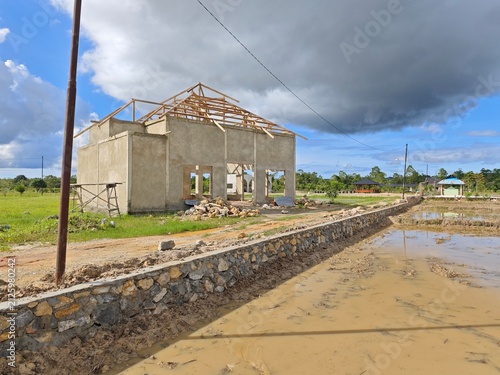 Obraz na plátne House building under construction with wooden roof frame in rural area under clo