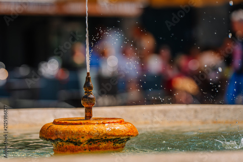 фотографія Ornate fountain with water spouting from the top, surrounded by blurred figures