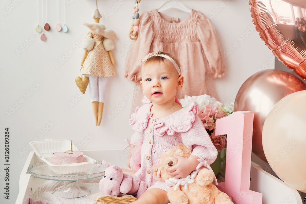 Fototapeta premium Adorable One Year Old Birthday Girl Celebrating First Birthday in Photo Studio with Cake, Balloons and Festive Decorations, Cake Smash Party, Happy Childhood Milestone Portrait