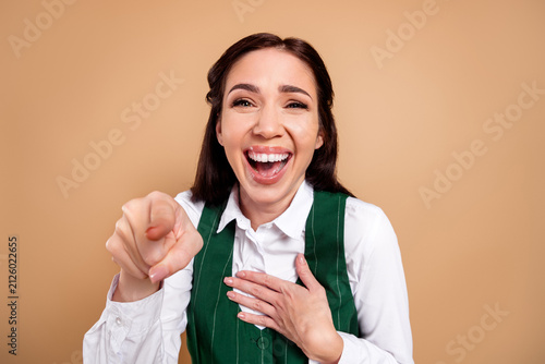 Fotografie Laughing woman pointing at camera with joyful expression and hand on chest, cand