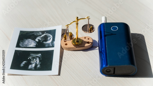 Foto Electronic cigarette scales and fetal ultrasound photos.