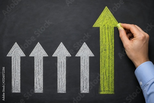 Hand drawing a green upward arrow on blackboard with growth chart concept