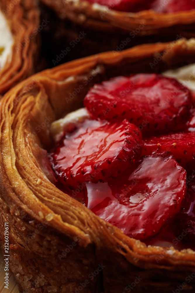 Obraz premium Macro detail of glossy strawberry slices and cream filling inside a crisp layered puff pastry tart