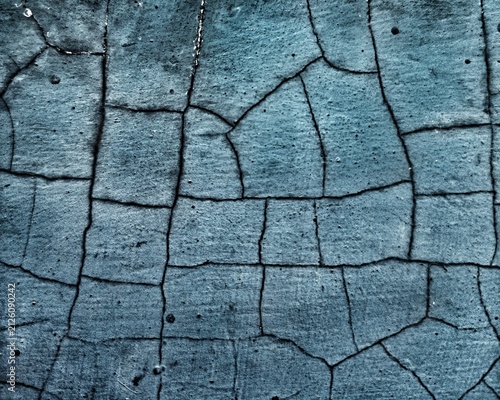 Abstract close-up texture of cracked blue concrete surface with deep fissure lines.