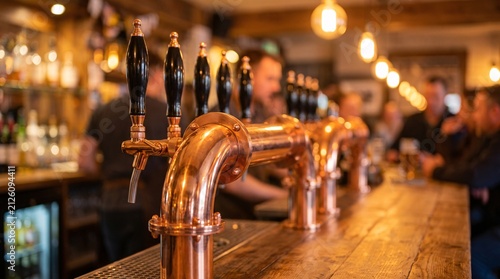 Shiny copper beer taps lined up on a wooden bar counter in a cozy dimly lit rustic pub