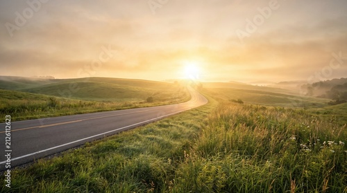 Winding asphalt road through green rolling hills during a golden sunrise