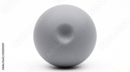 Single matte grey sphere featuring central indentation isolated against a clean minimalist white background with positioned centrally against circular dimple positioned