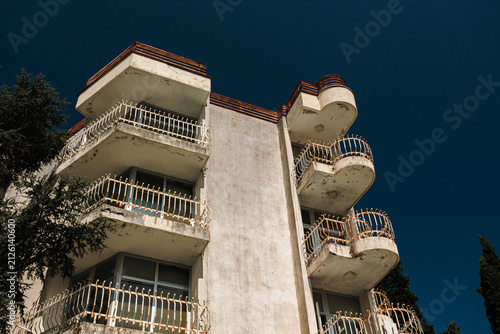 Canvas Print Weathered apartment building featuring multiple balconies under a clear blue sky