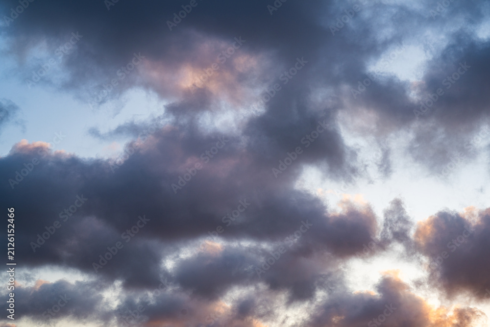 Obraz premium Dramatic evening sky with dark clouds and warm sunset light 