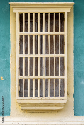 Colonial Style Window with Wooden Bars on Blue Wall. Window with Blue Bars on Yellow Wall