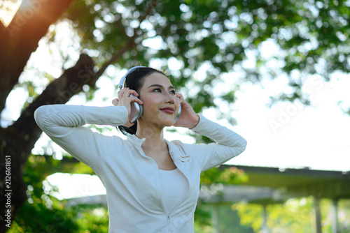 Quadro su tela Woman enjoying music with headphones in park, uplifting wellness moment