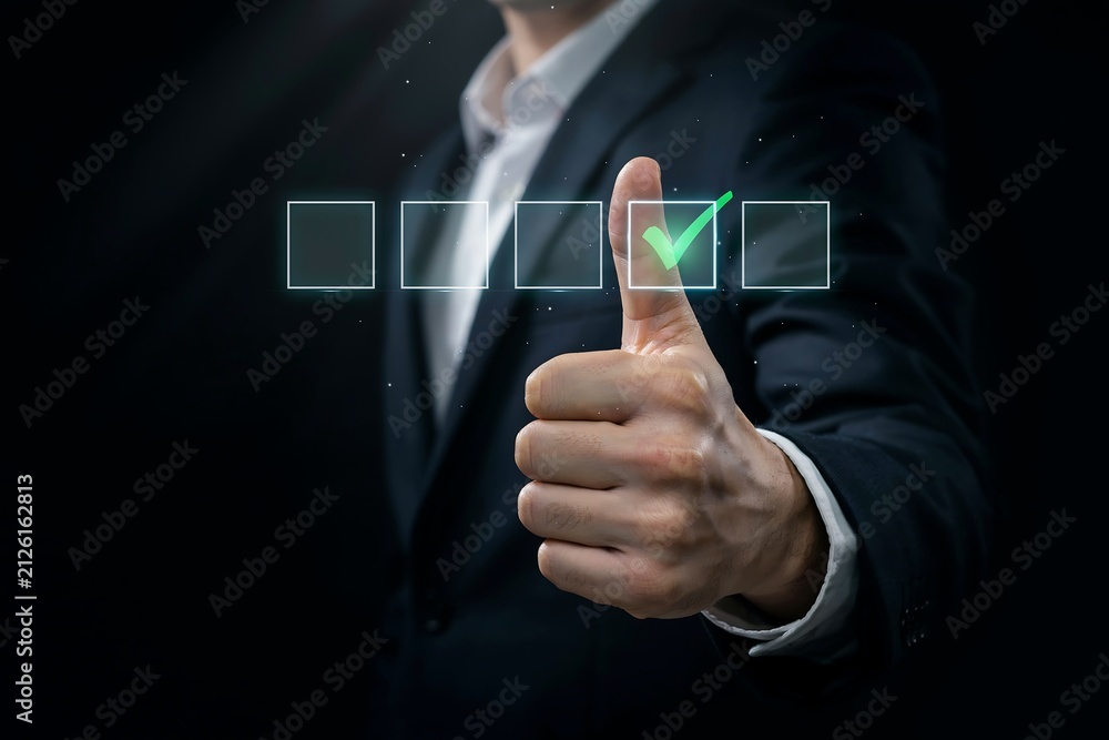 Fototapeta premium Person gives a thumbs-up gesture next to a glowing green checkmark in a digital checklist.