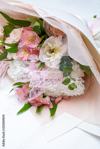 Female Hand presents Elegant bouquet of mixed roses and blossoms in soft pinks and white tones