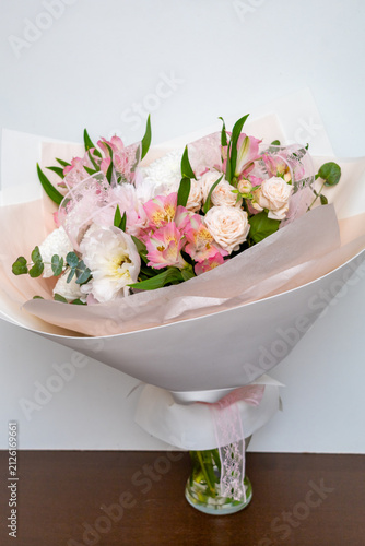 Female Hand presents Elegant bouquet of mixed roses and blossoms in soft pinks and white tones