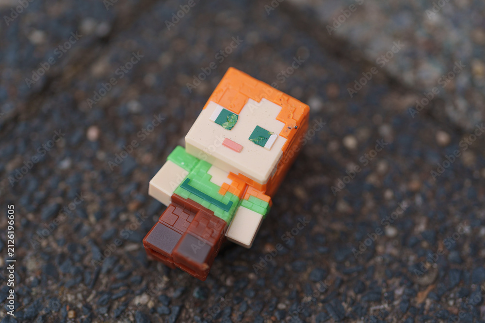 Fototapeta premium Dusseldorf, Germany - July 23 2026: Minecraft Alex figurine resting on pavement outdoors