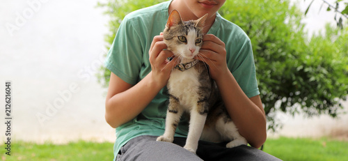 Teenager hugging a cat outdoors: friendship and love between a young person and their pet