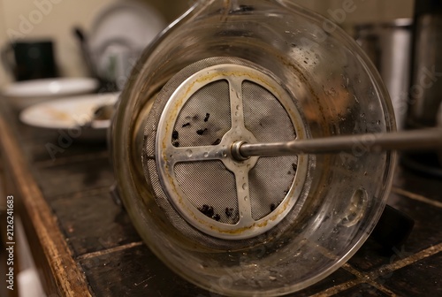 Close up of a glass french press coffee maker mesh plunger with coffee stains