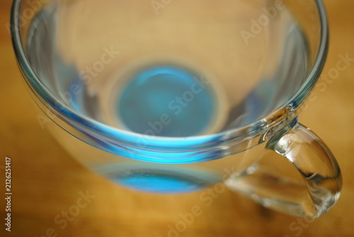 Full blue transparent glass of water on a wooden table.