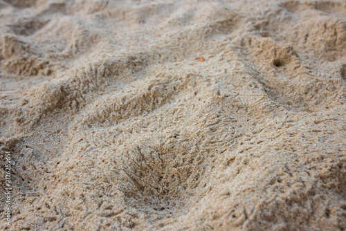 Fotografie Soft beach sand texture with shallow footprints and fine grain creating warm coa