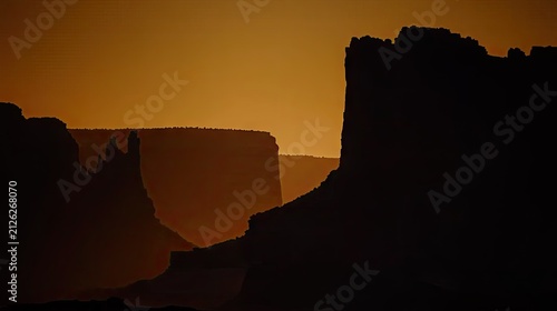 Dramatic layered silhouettes of arid rock formations dominate the warm evening sky