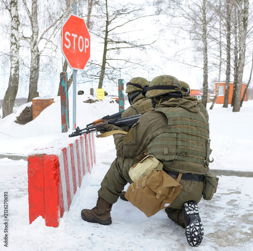 Canvastavla Armed Ukrainian soldiers aiming Kalashnikov assault rifle near stop sign on mili