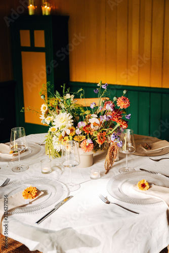 Festively Decorated Dining Table with Fresh Floral Arrangement, Elegant Event Setup in Soft Natural Daylight