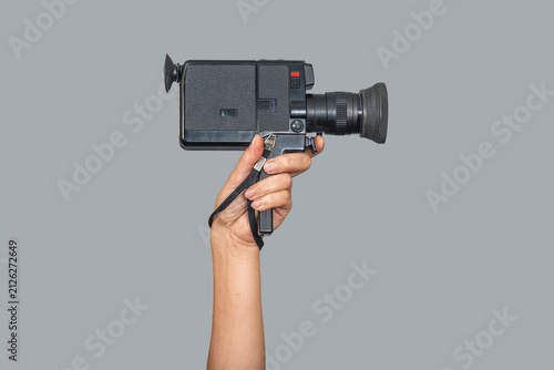 Retro video camera in hand, vintage paparazzi video recording device, isolated on gray background.