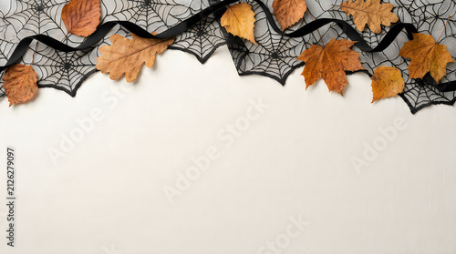 Halloween flat lay border with black spider webs and autumn leaves, spooky seasonal background, decorative fall foliage on white surface Halloween