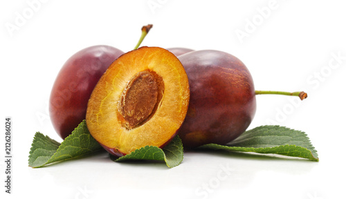 Quadro su tela Fresh ripe plum fruit with half and leaves isolated on a white background
