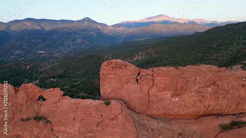 Drone flying slow next to huge Garden of the Gods rock formation with mountains in the background