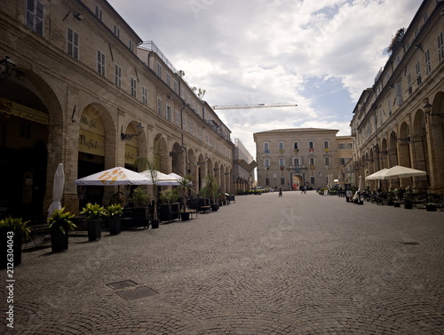 Принти на полотні Elegante piazza con portici storici, colonne in pietra e locali all’aperto, ripr