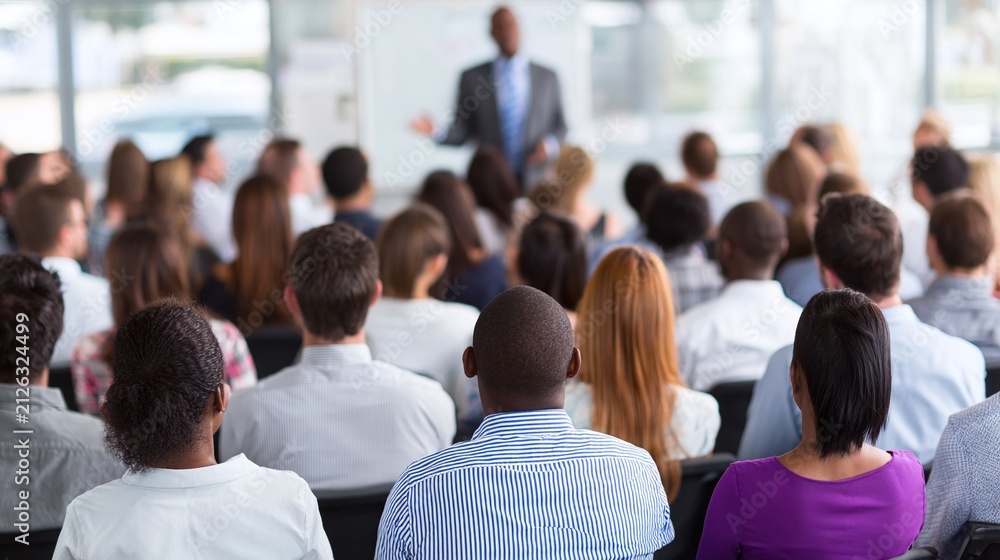 Obraz premium Diverse Group of Professionals Listen Attentively to a Speaker in a Modern, Bright Conference Room, Focused on Education and Business Development