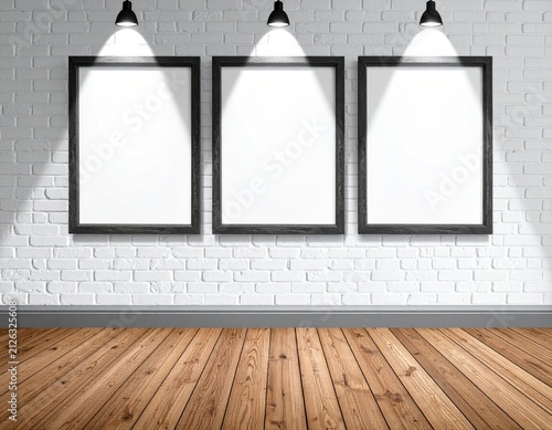 Three blank picture frames on a white brick wall, spotlighted, with wooden floor