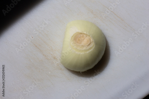 Small piece of white onion with root on cutting board