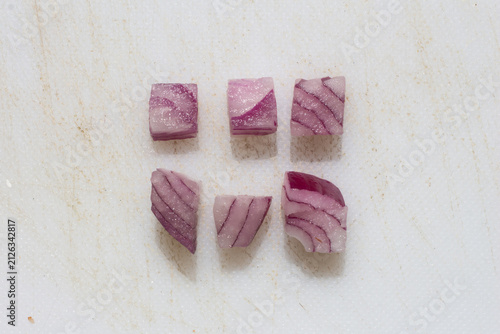 Neatly arranged diced red onion cubes on white background