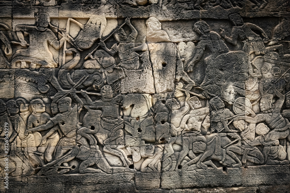 Fototapeta premium Ancient sandstone bas-relief depicting a historical battle and warriors on the walls of Bayon Temple in Angkor Thom, Siem Reap, Cambodia
