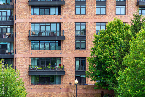 Modern brick apartment building facade with balconies and trees in Boston residential neighborhood