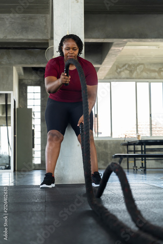Cuadro en lienzo Plus size African American woman doing battle rope exercise in modern gym, fitness lifestyle photo for cardio strength workout, healthy routine, endurance, body positivity and wellness motivation