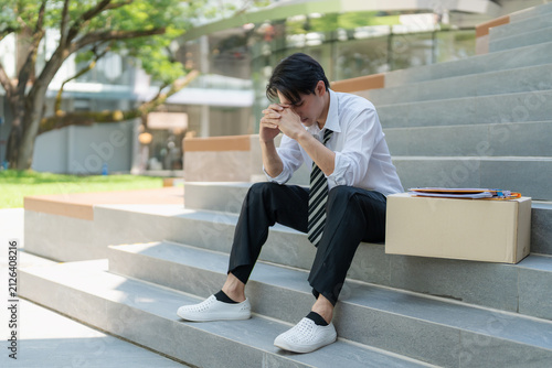 Foto Unemployed man sitting on stairs holding resume feeling stressed and hopeless after getting fired