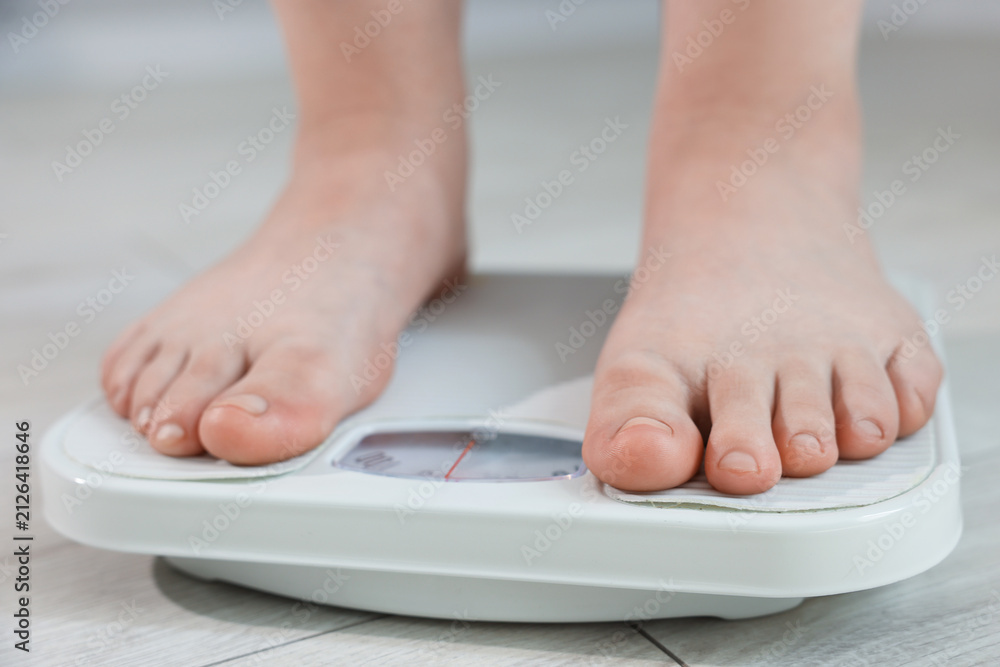Fototapeta premium Overweight woman on scale at home, closeup