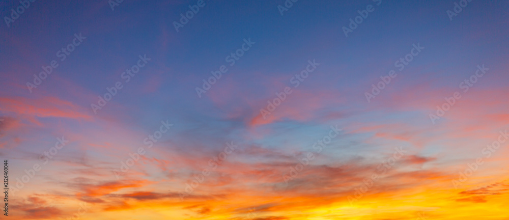 Fototapeta premium Vibrant colorful sunset sky with dramatic clouds and glowing gradient twilight horizon,A breathtaking panoramic view of a vibrant colorful sunset sky filled with dramatic wispy clouds, transitioning.