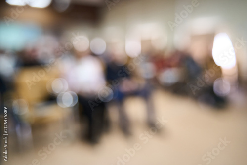 Audience Seated Listening Lecture Hall Conference Attendees In Auditorium Front Row Out Of Focus During Corporate Seminar With Blurred Figures Shallow Bokeh And Warm Indoor Lighting.