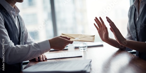 Businesspeople in corporate office showing rejection of bribe envelope, hand stop gesture and corrupt money offer, representing anti corruption policy and ethical decision making