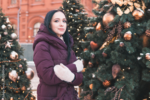 Photography Woman touching Christmas tree decoration on snowy Moscow street